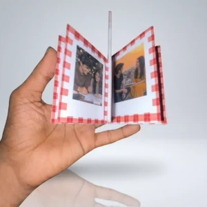 9Wicks mini polaroid photo album book with a red gingham border being held open in a hand to show couple pictures.